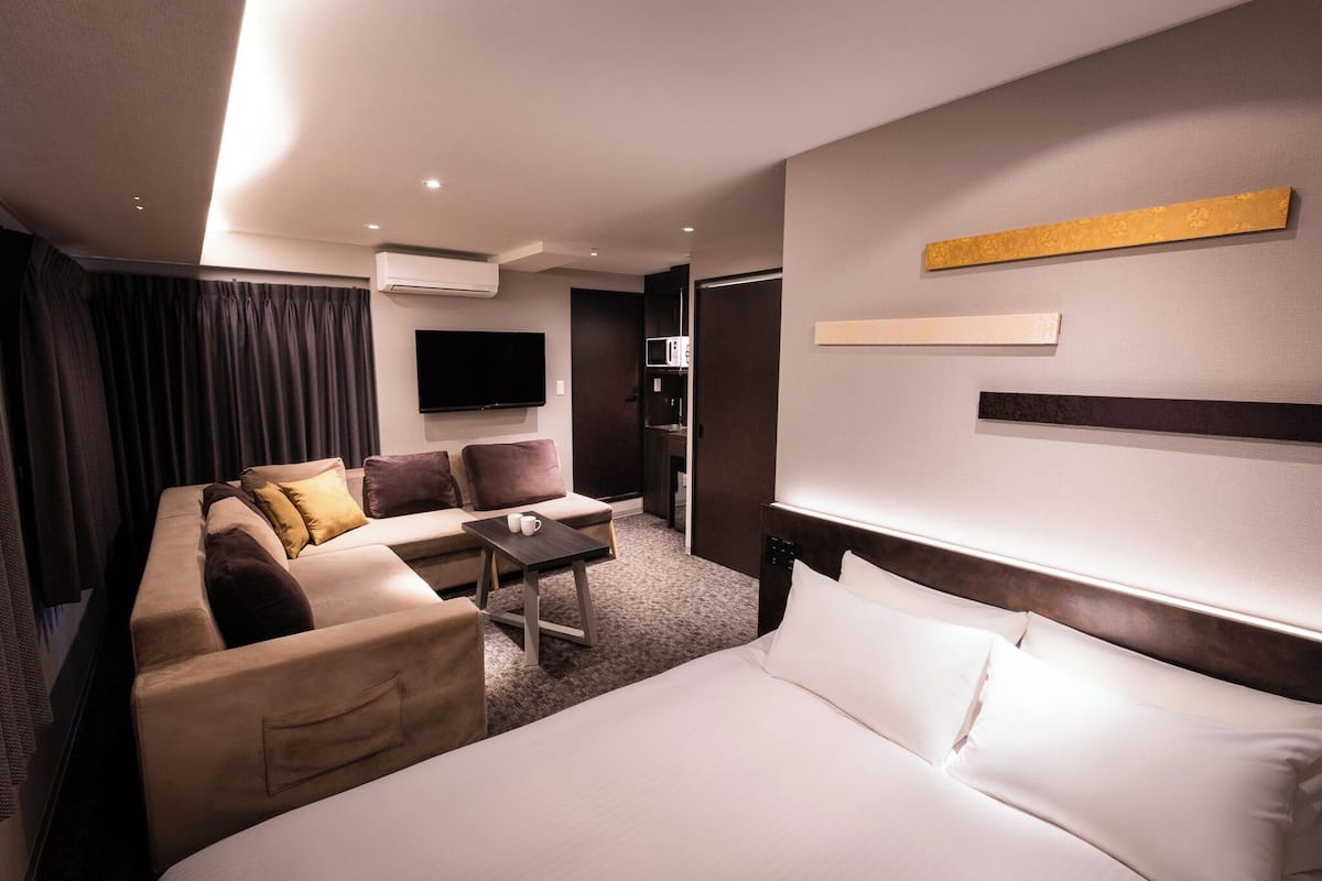 Une chambre d’hôtel avec un lit, un canapé, une table basse et un téléviseur.