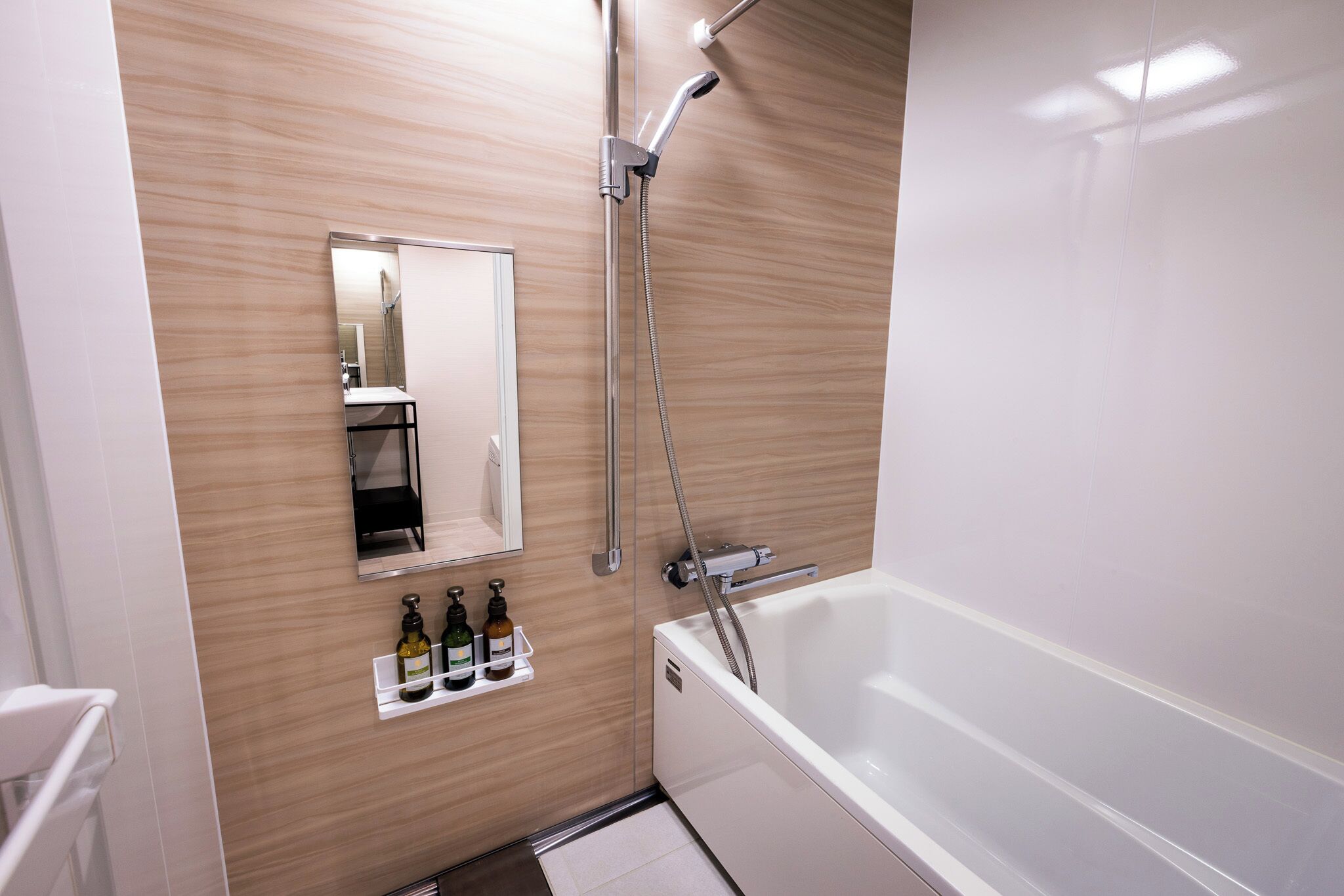 Un baño moderno con pared de madera, un espejo grande, una bañera y una ducha.