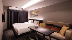 Une chambre d’hôtel avec un lit, un canapé, une petite table et un téléviseur fixé au mur.