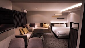 Une chambre d’hôtel moderne équipée d’un canapé, d’un lit, d’une petite table et d’un téléviseur.
