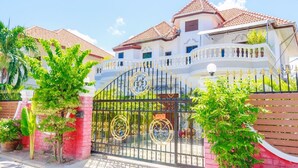 A large, multi-story house with a gated entrance, surrounded by lush greenery. - Ratana Villa - Pattaya Holiday House Walking Street (Pattaya)