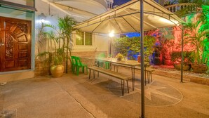An outdoor patio with a covered dining area, green chairs, and potted plants. - Ratana Villa - Pattaya Holiday House Walking Street (Pattaya)