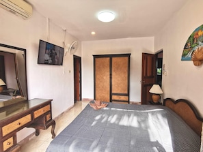 A bedroom with a bed, dresser, mirror, and a door leading to another room. - Baan Kanittha - 5 Bedrooms Pool Villa (Pattaya)