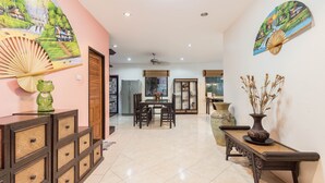Un espacio habitable amplio con una mesa de comedor, un sofá y un ventilador decorativo.