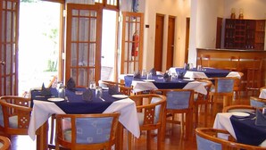 Un restaurant doté de nombreuses tables et chaises, d’un plancher en bois et offrant une vue sur l’extérieur grâce à de grandes fenêtres.