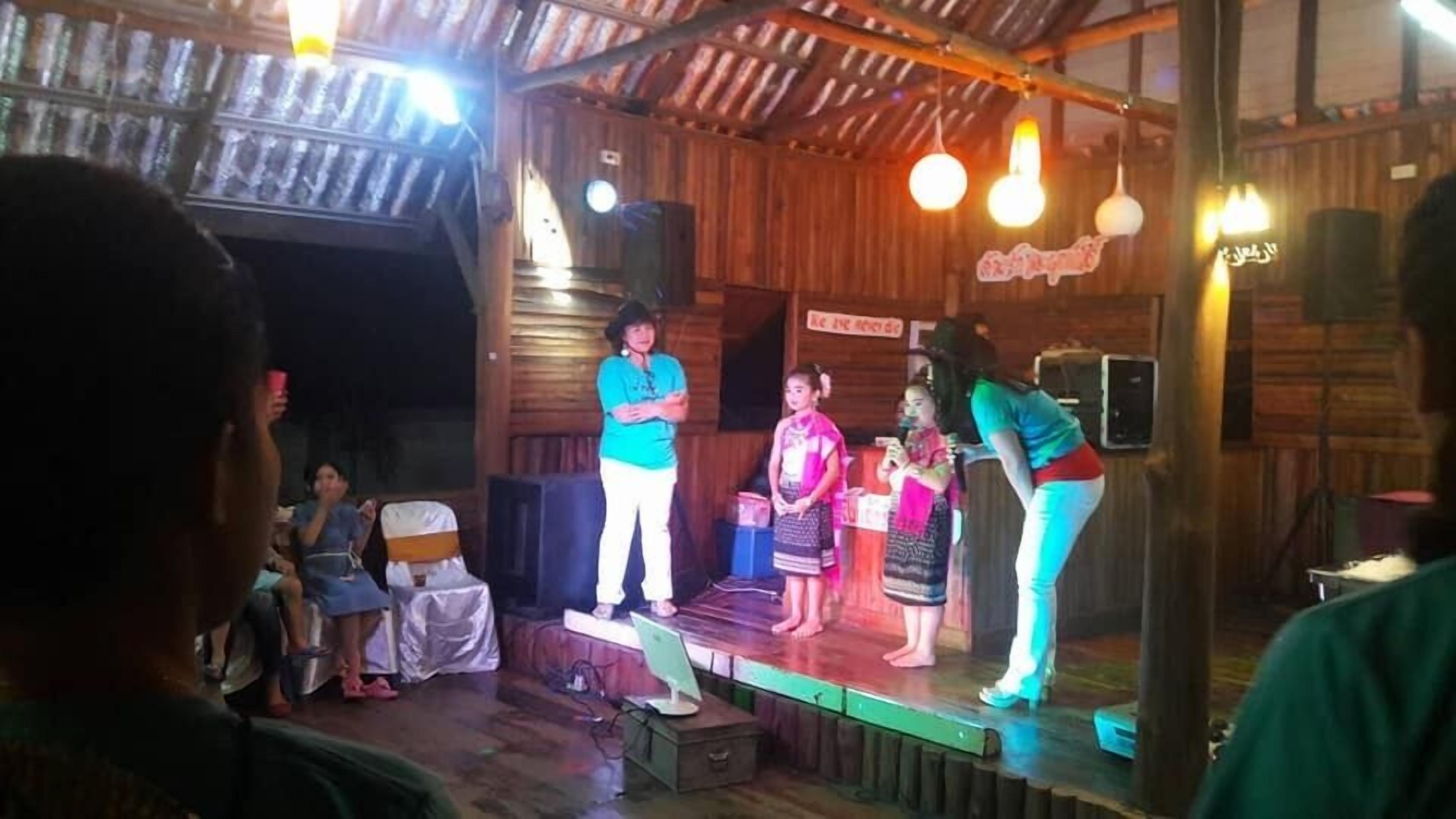 A stage with a wooden backdrop, a microphone stand, and a few people on stage.