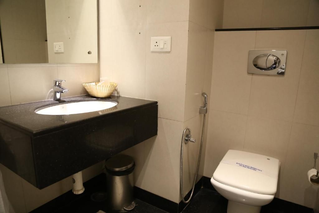 Een badkamer met een zwart wastafel, een wit toilet en een douche.