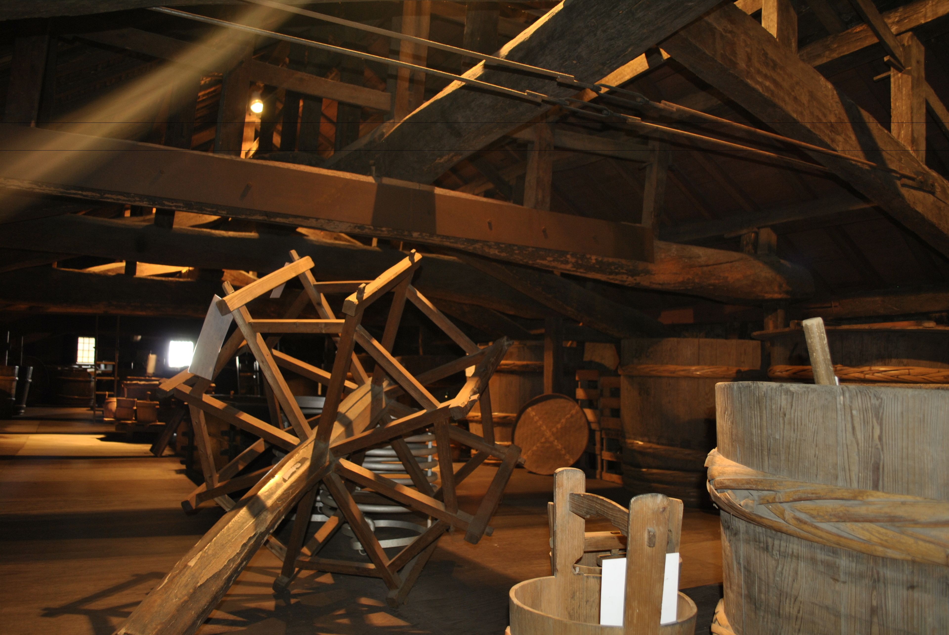 Una gran estructura de madera, posiblemente un molino o edificio histórico, con vigas y ruedas.