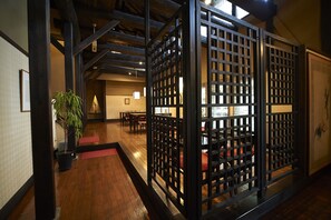Een traditioneel Japans interieur met tatami vloeren, een shoji-scherm en een receptiegedeelte met een rode mat.