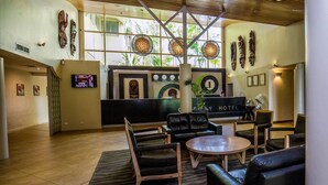A hotel lobby with a reception desk, seating area, and decorative wall art. - Gateway Hotel (Port Moresby)