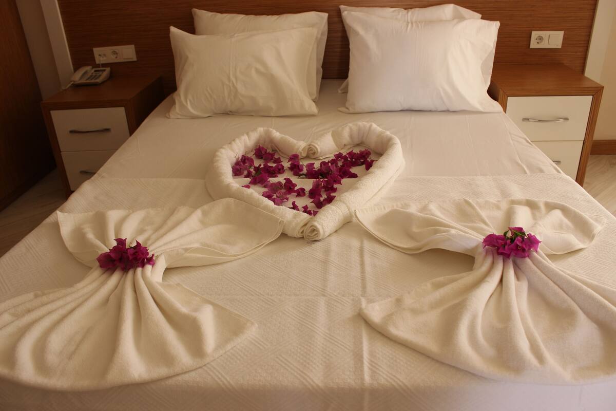 A neatly made bed with heart-shaped floral arrangements on the bedspread.