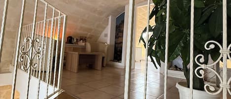 A spacious room with a tiled floor, a wooden bench, a potted plant, and a white railing.