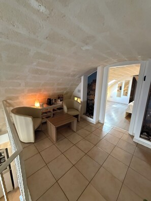 Un vaste espace de vie doté d’un haut plafond, d’une cheminée, d’un canapé et d’une table basse.
