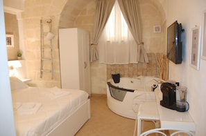 Une chambre d’hôtel avec un lit, un bureau, une baignoire et un téléviseur.