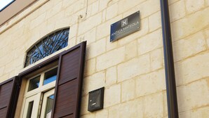 A building with a stone facade, a window with decorative ironwork, and a sign for "ANTICA MATEOLA ROOMS & SQUATS." - Antica Mateola Rooms&Suites (Matera)