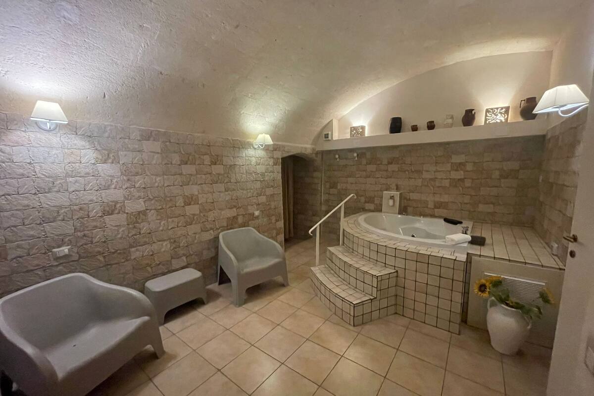 Een badkamer met een stenen muur, een bad, douche, wastafel en toilet.