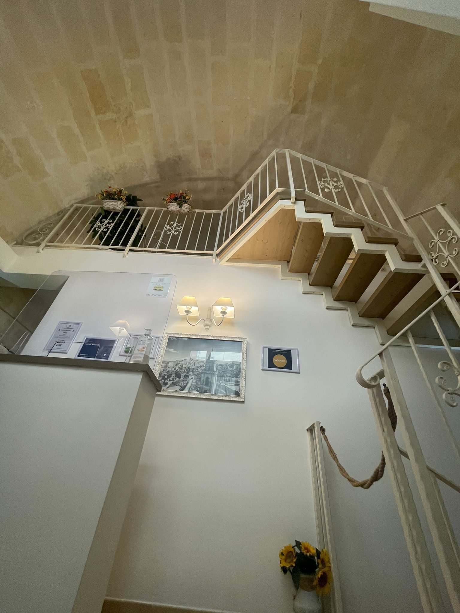 A staircase with a white railing, a framed picture on the wall, and a small sign.