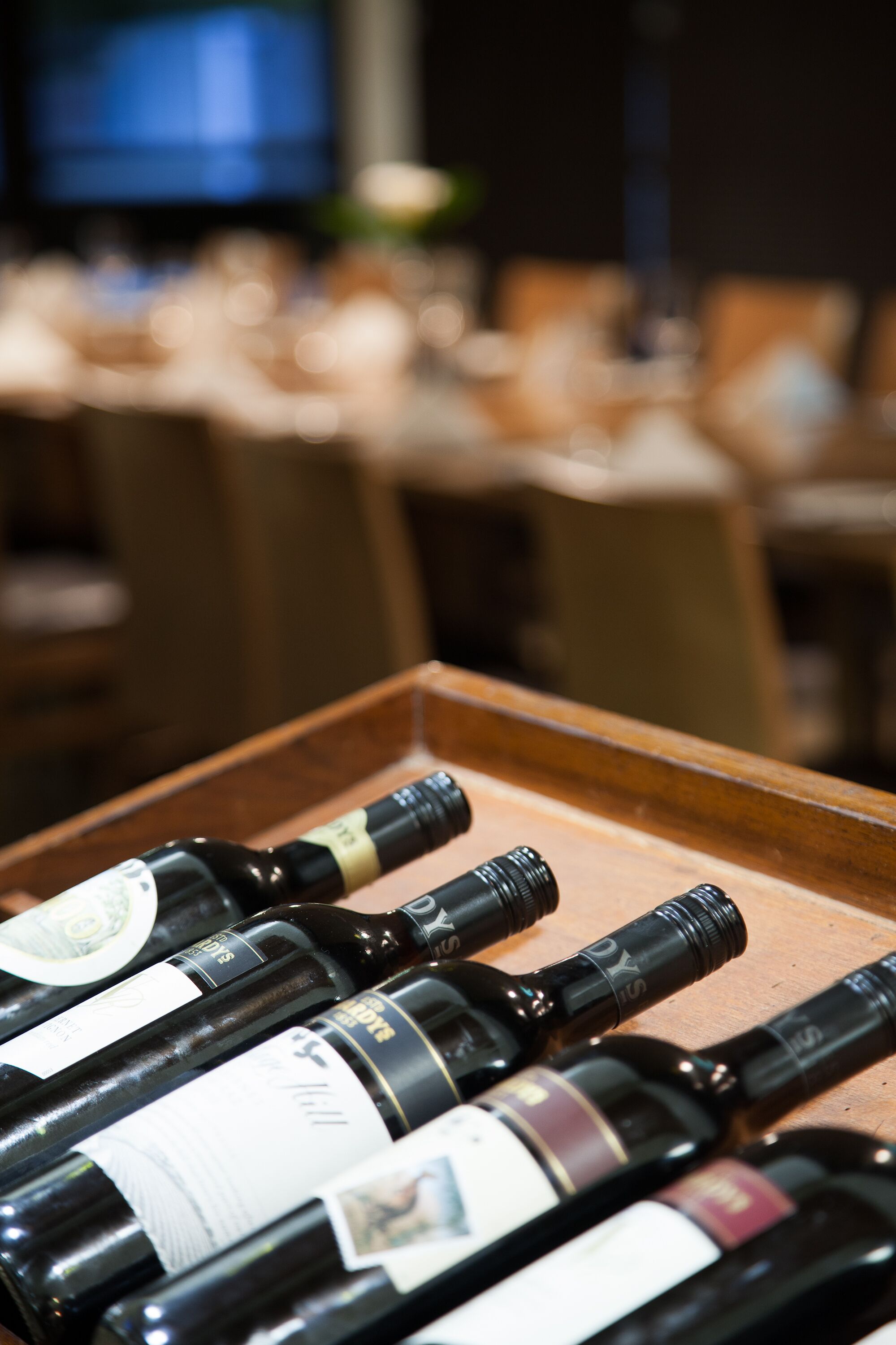 Une barquette de bouteilles de vin sur une table en bois, dans une pièce à la lumière tamisée, avec un arrière-plan flou.