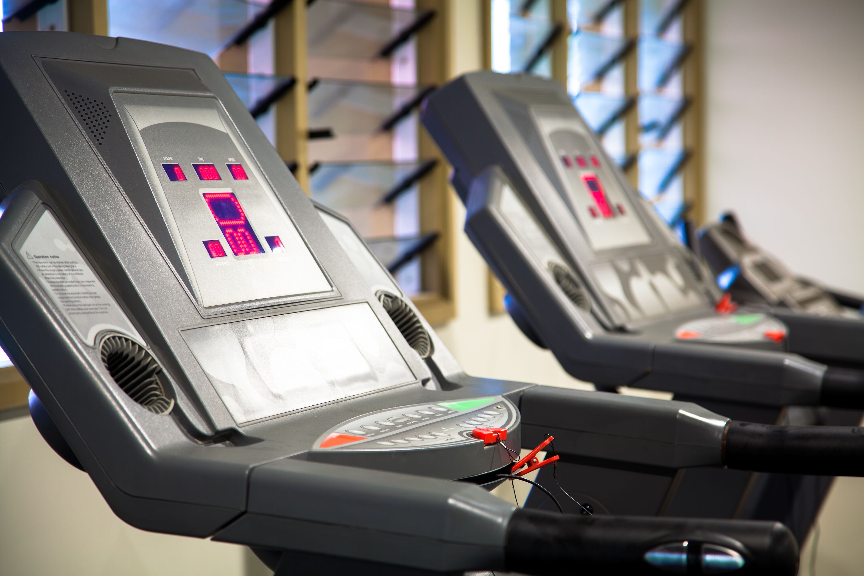 A row of stationary exercise bikes with digital displays and control panels.