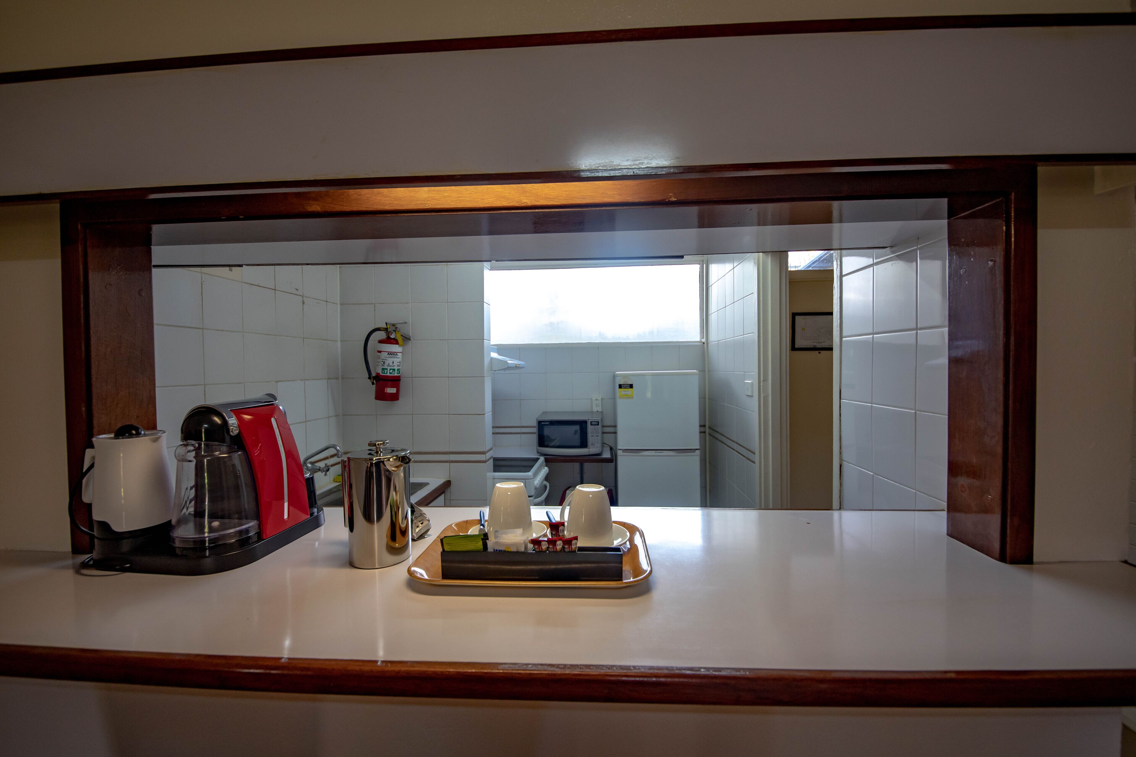 A kitchen with a coffee maker, microwave, and a tray with cups and a teapot.