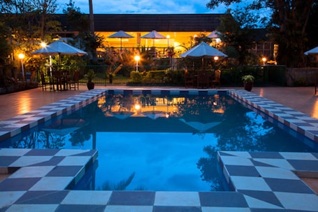 Una piscina al aire libre, sombrillas, sillones reclinables de piscina