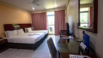 A hotel room with a bed, a desk, a chair, a television, and a window with curtains.