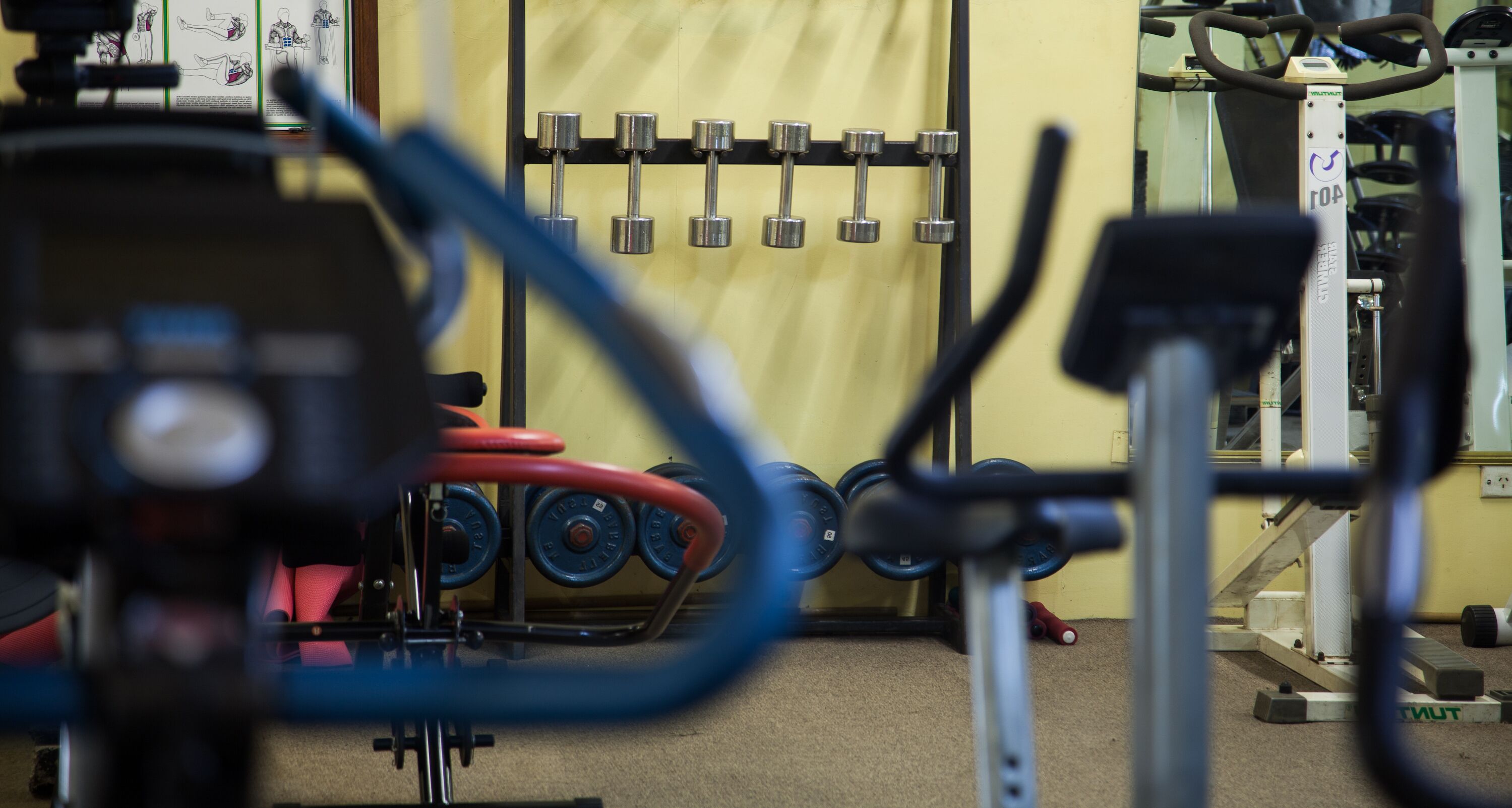 A gym with exercise equipment, including dumbbells on a rack and a stationary bike.