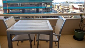 Ein Balkon mit Tisch und Stühlen, mit Blick auf eine Stadtlandschaft, einschließlich Gebäude wie eine Bank und ein DJ Haus.