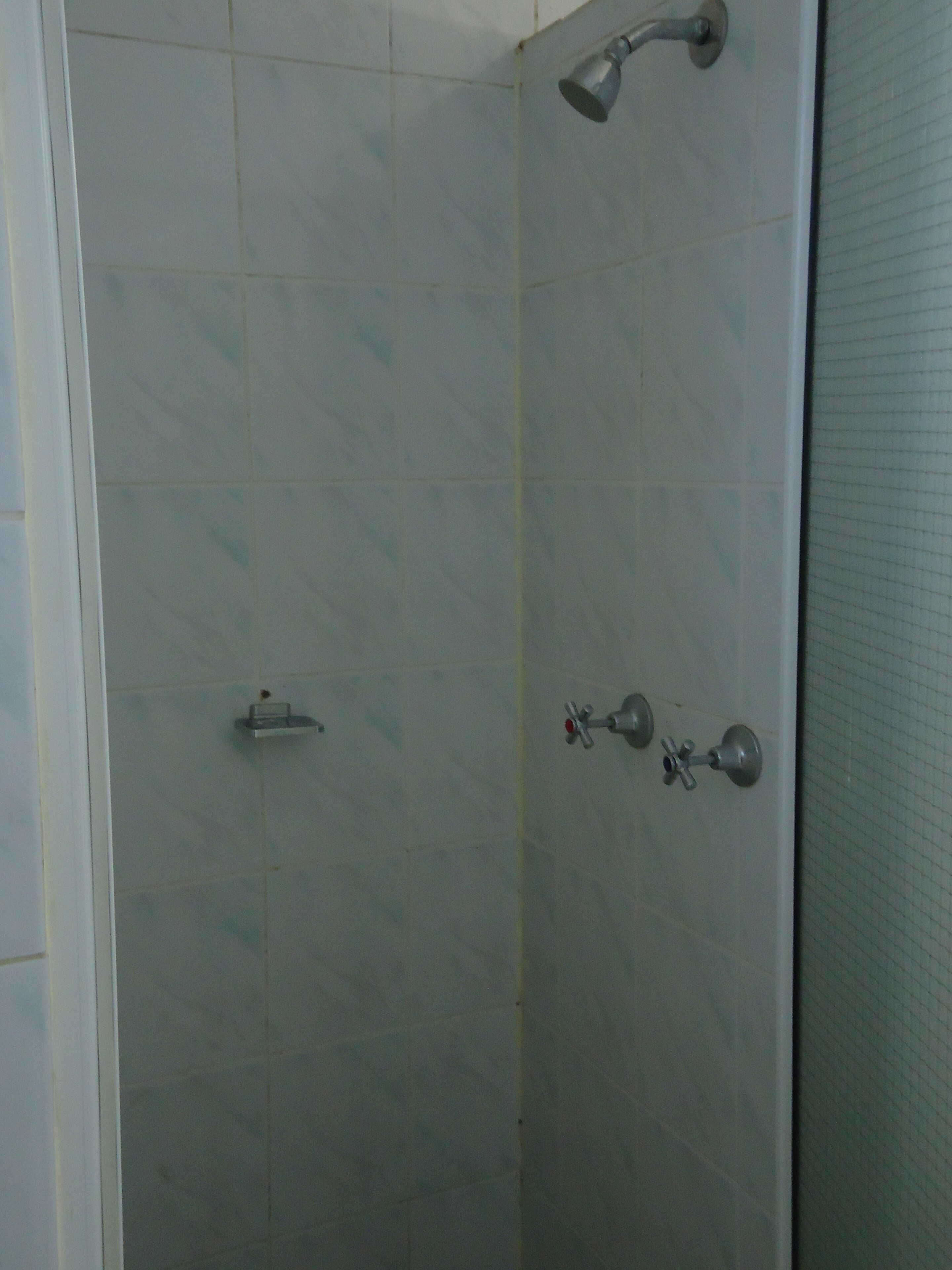 A shower area with a handheld showerhead and a wall-mounted faucet.