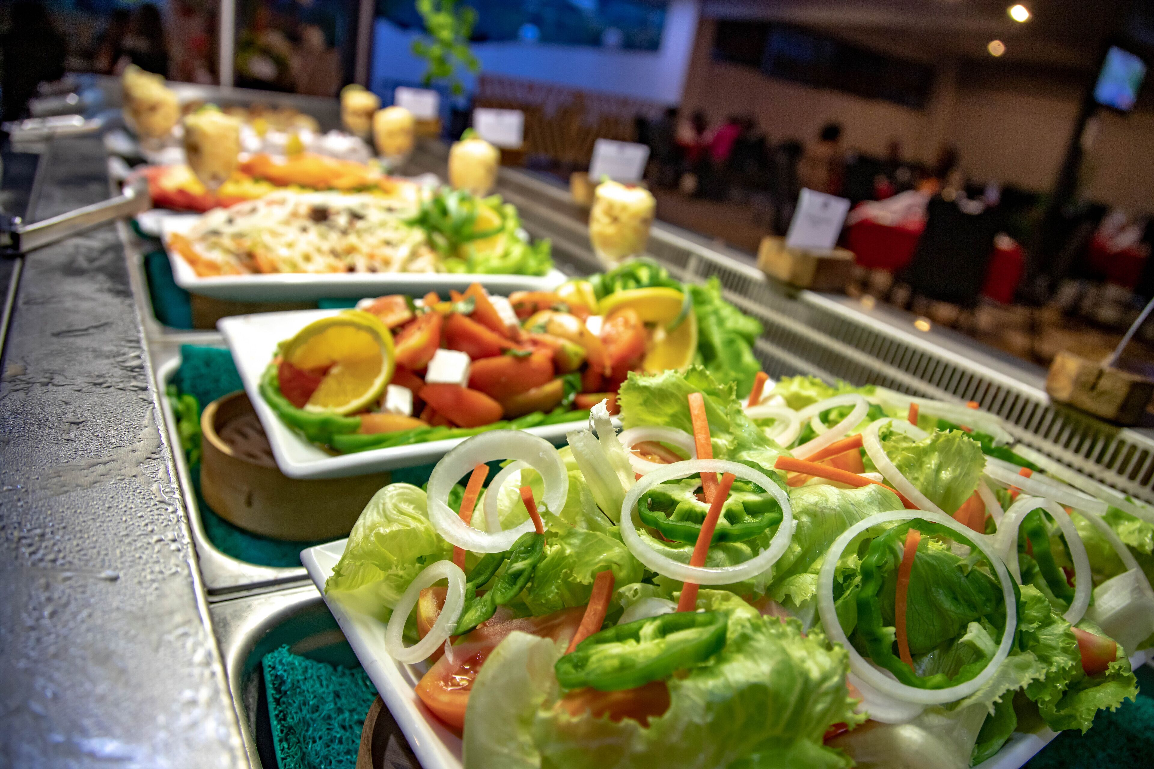 A buffet with various dishes including salads, sandwiches, and other prepared foods.