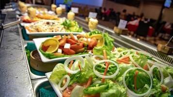A buffet with various dishes including salads, sandwiches, and other prepared foods.