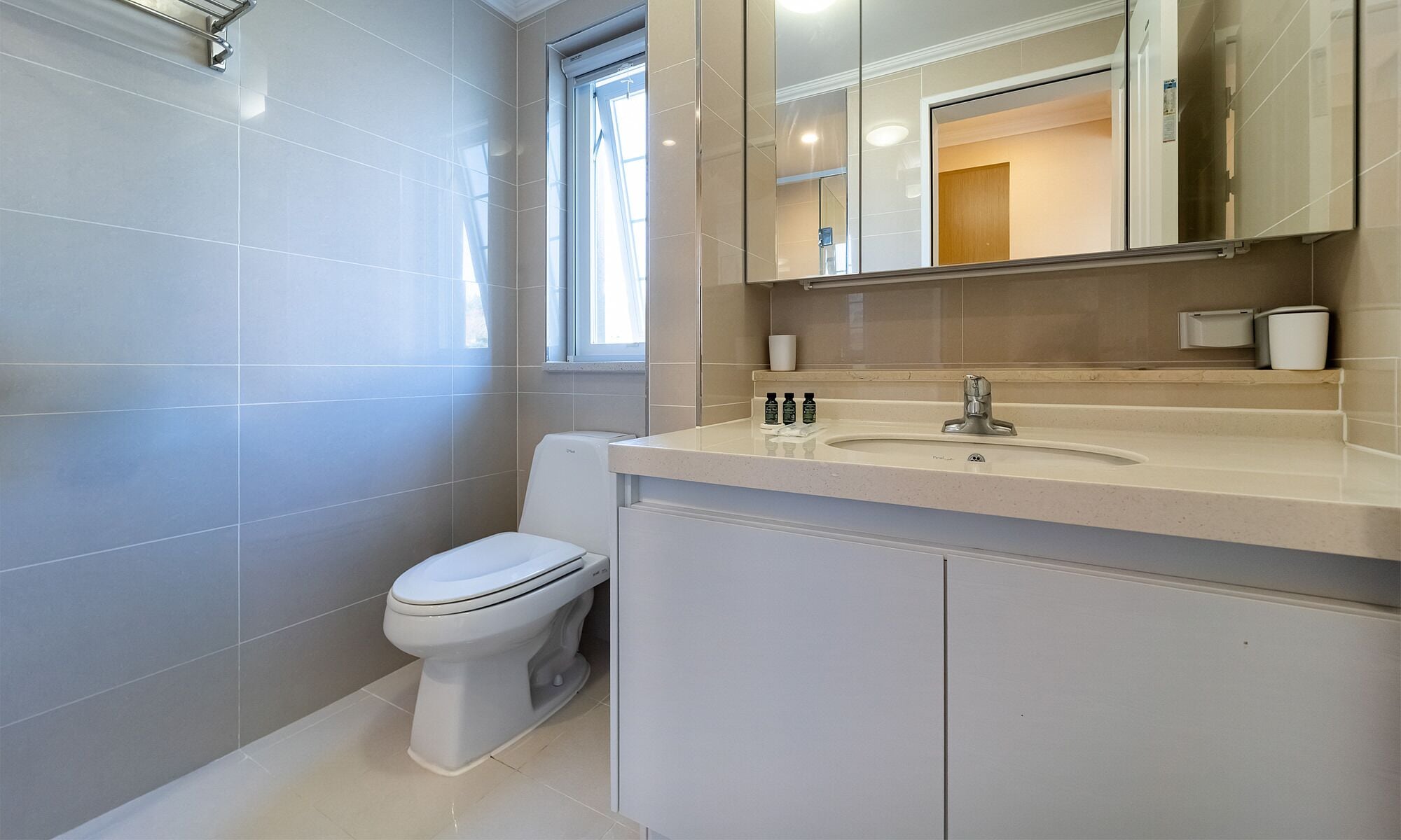A modern bathroom with a toilet, sink, and mirror.