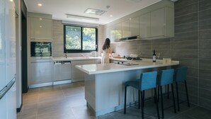 Una cocina moderna con una isla central, taburetes de bar y vistas al exterior a través de una ventana.