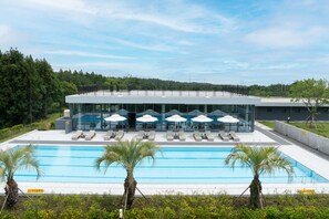 Een modern hotel met een groot zwembad, ligbedden en parasols.
