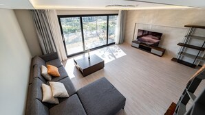 Una sala de estar moderna con un sofá seccional gris, una mesa de centro, un televisor de pantalla plana y una chimenea.