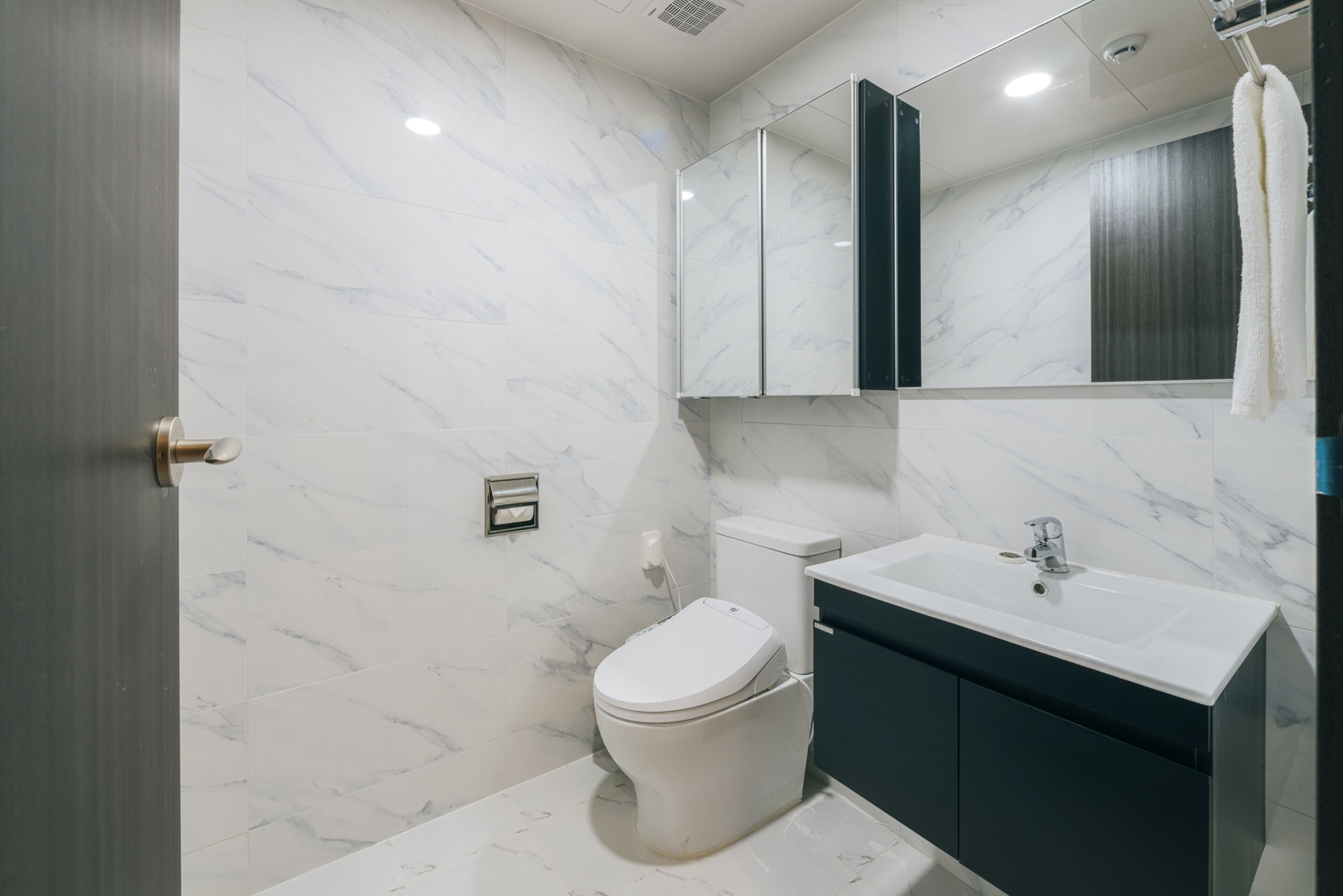 A modern bathroom with a toilet, sink, and mirror.