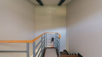 A staircase with wooden handrails and a grey metal railing, leading to a landing with a circular light fixture.