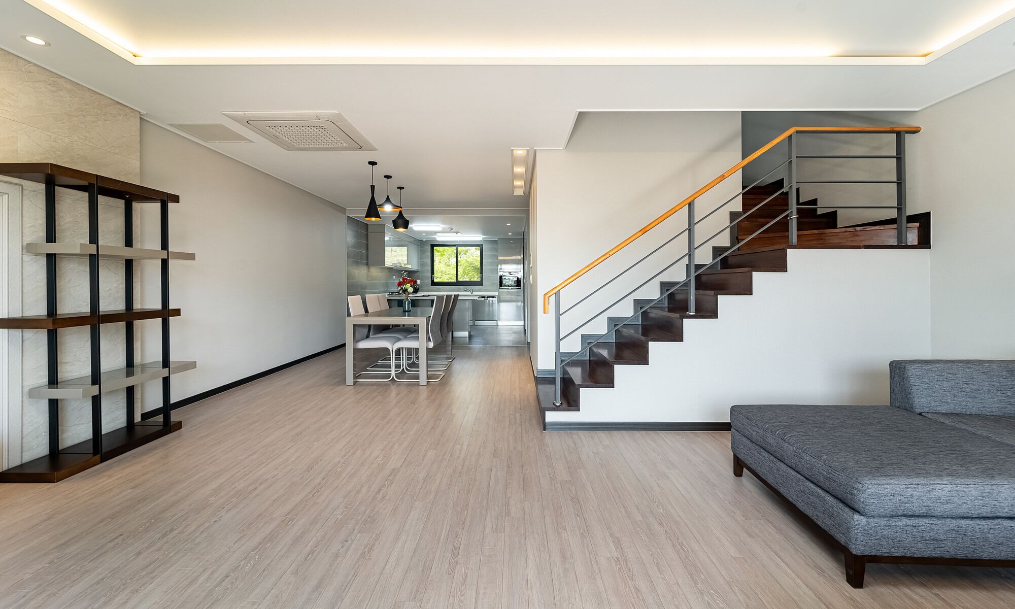 A modern interior with a staircase, a dining area, and a living room.