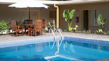 Una piscina al aire libre, sombrillas, sillones reclinables de piscina