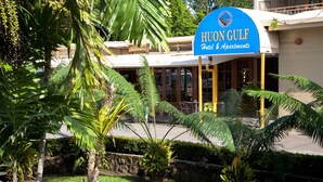 Hoon Gulf Hotel & Apartments -hotellin ulkonäkö, jossa on näkyvillä kyltti. Hotellin ympärillä on vehreää kasvillisuutta ja palmuja.