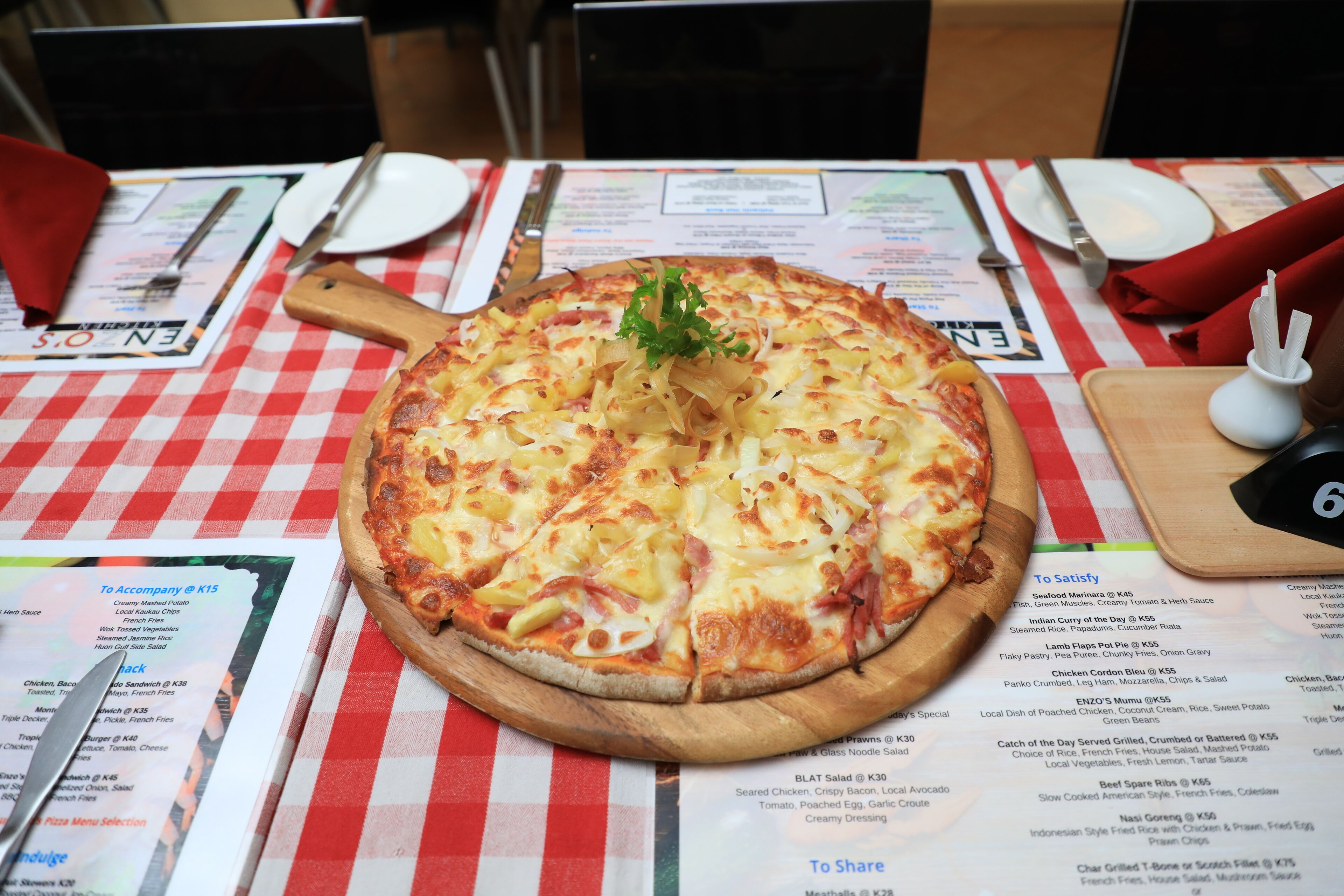A pizza on a wooden board with a menu in the background.