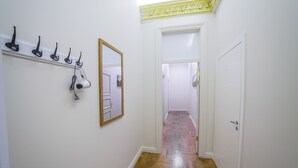 A hallway with a wooden floor, white walls, and a mirror on the left. - Mosaic Center Apartments (Riga)