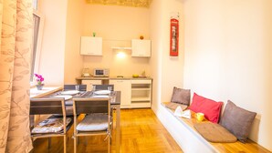A compact living space with a dining area, kitchenette, and a seating area with cushions. - Mosaic Center Apartments (Riga)