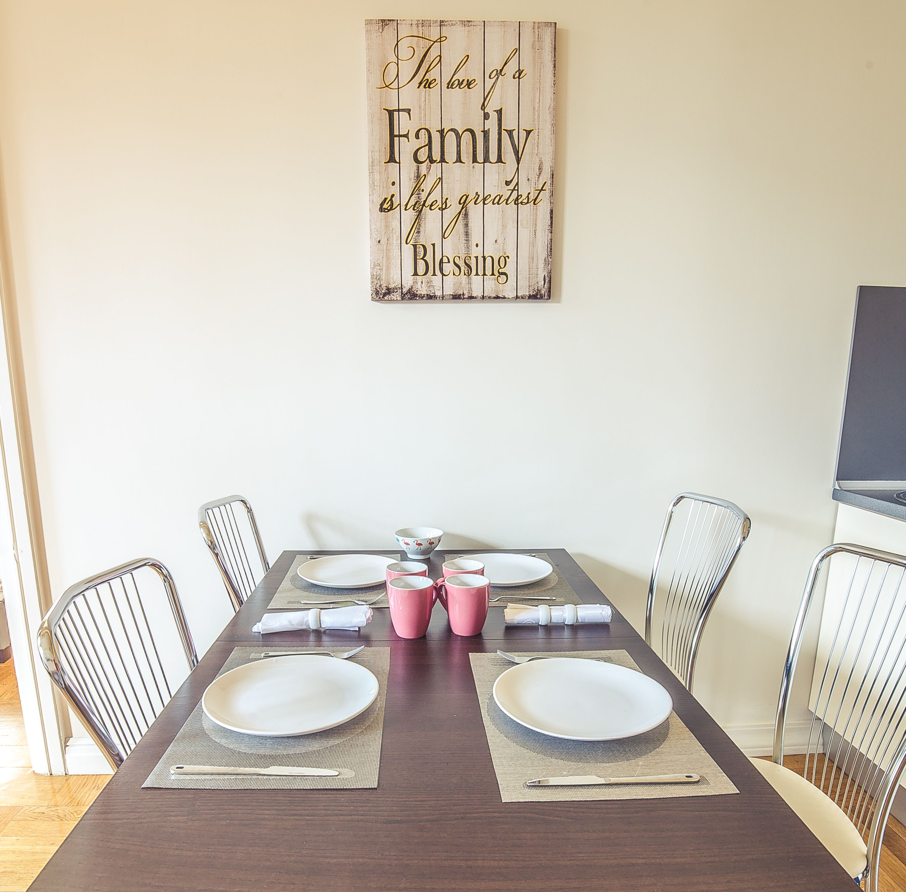 A dining room with a wooden table set for six, surrounded by metal chairs.