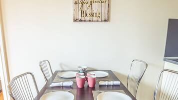 A dining room with a wooden table set for six, surrounded by metal chairs.
