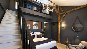 A modern hotel room with a staircase, a large bed, a seating area, and a view of the city. - Hotel Square Louvois (Paris)