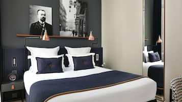 Una habitación de hotel moderna con una cama grande, dos lámparas de noche, una mesita de noche, un espejo y dos cuadros colgados en la pared.