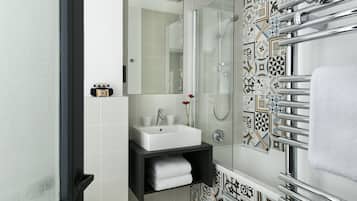A modern bathroom with a white sink, a glass shower enclosure, and a patterned tile backsplash.