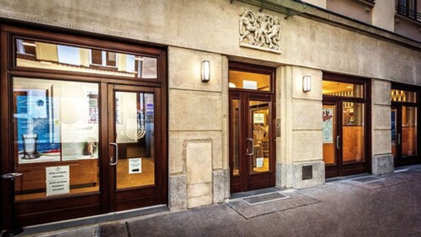 A building with large glass windows and wooden doors, featuring a stone facade and a decorative emblem above the entrance. - Hotel Kazimierz III (Kraków)