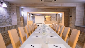 A conference room with a long table, chairs, and a projector screen. - Hotel Kazimierz III (Kraków)